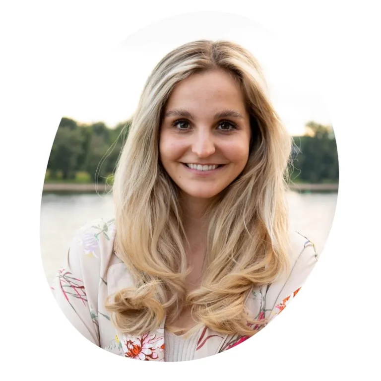 Ein kreisförmig zugeschnittenes Porträtfoto von Catharina Minz-Hofmann. Sie ist Zyklus-Expertin und Marketingleitung der trackle GmbH. Sie hat langes blondes Haar und lächelt freundlich vor einem Hintergrund, der einen See und Bäume bei Sonnenuntergang andeutet. Das Foto unterstreicht die fachliche Kompetenz im trackle-Team.